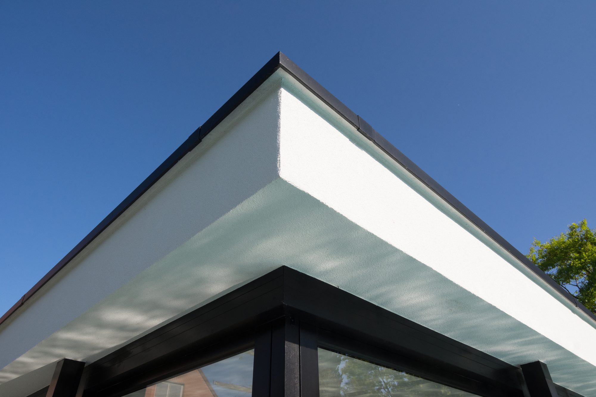 Dakrand in witte crépi met zwart aluminium dakprofiel