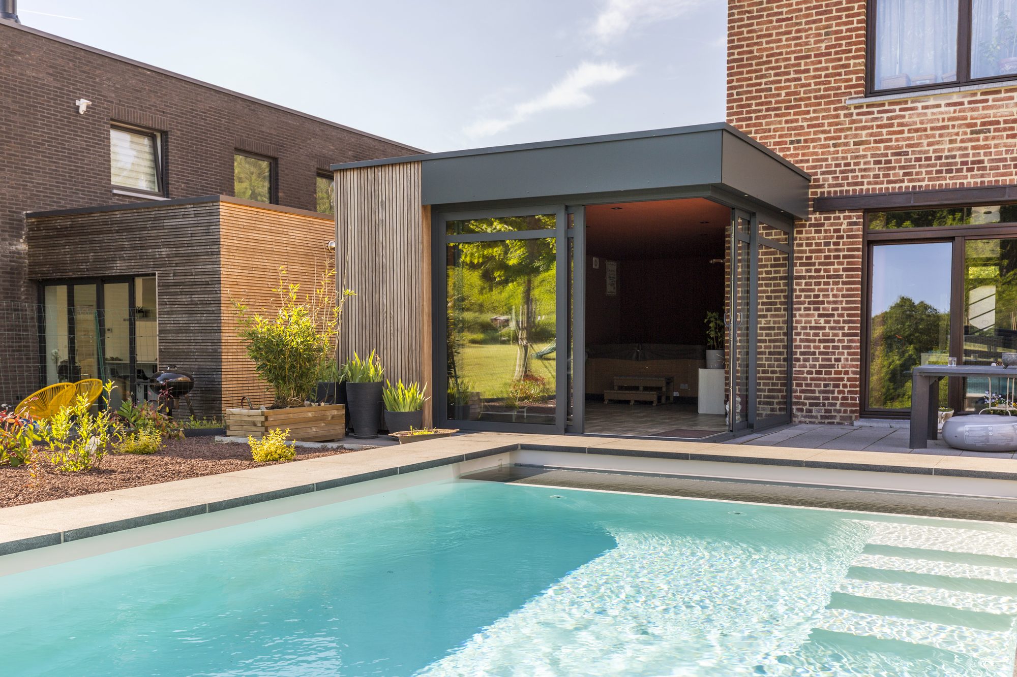 Extension de Maison avec des fenêtres en aluminium, bandeau en Trespa et lattes de finition en Afrormosia
