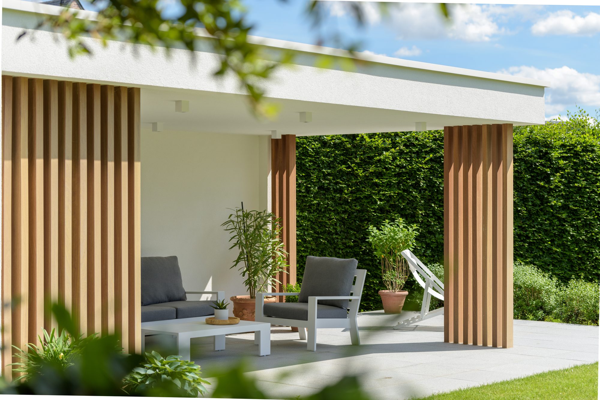 Moderne tuinkamer in witte crepi en met iroko houten palen