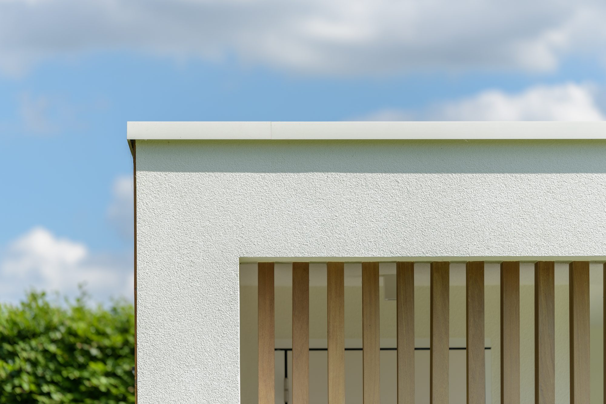 Aluminium dakprofiel bij moderne poolhouse in witte crepi en met irokohout