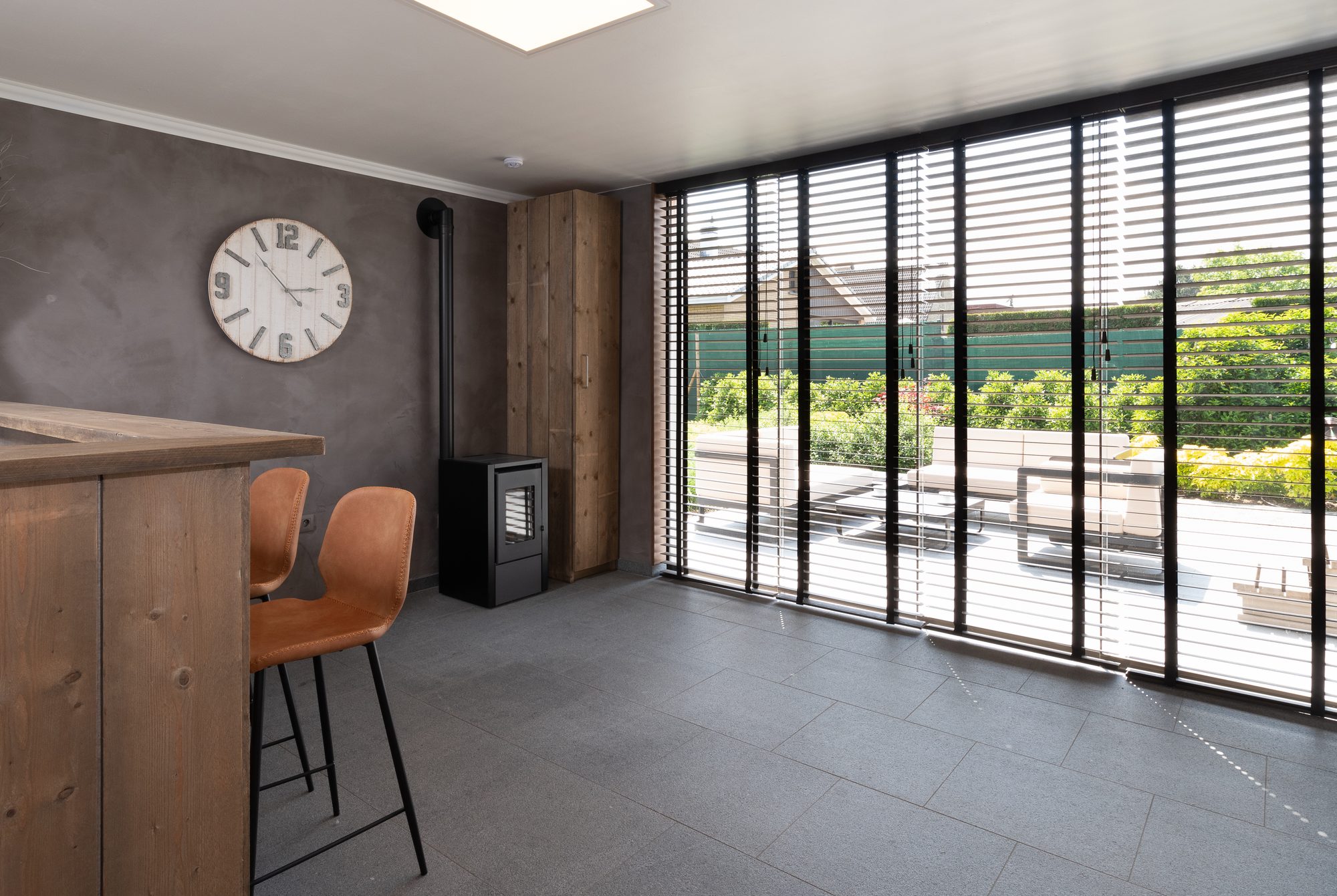 Interieur tuinkamer met bar, schuiframen en kachel
